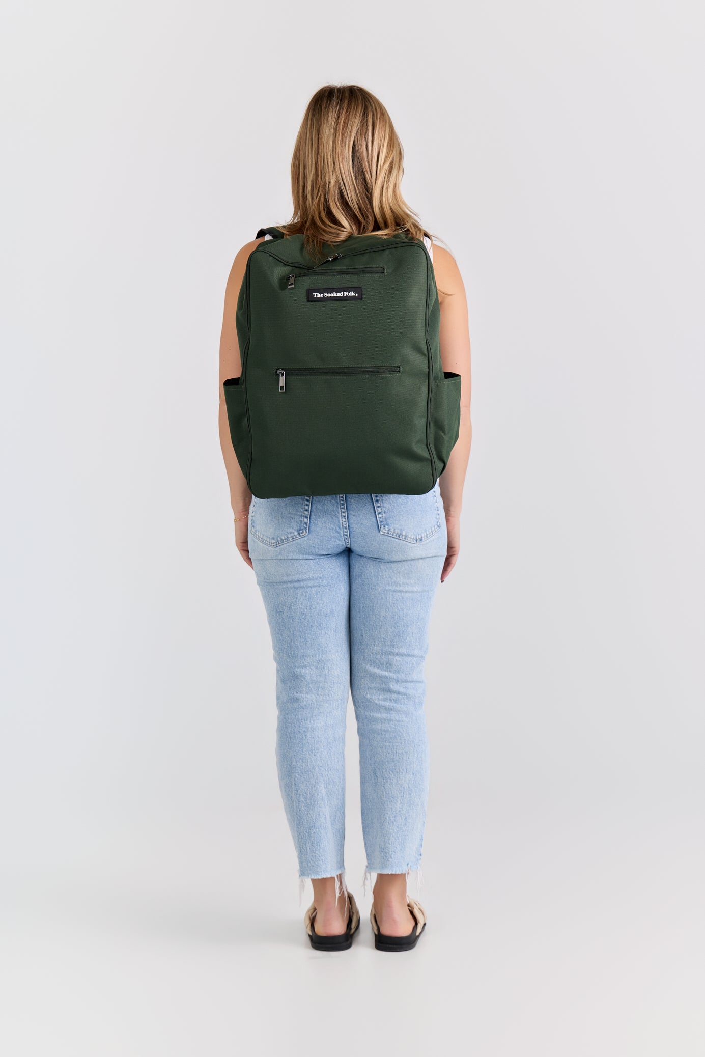 Person wearing a green backpack on a white background