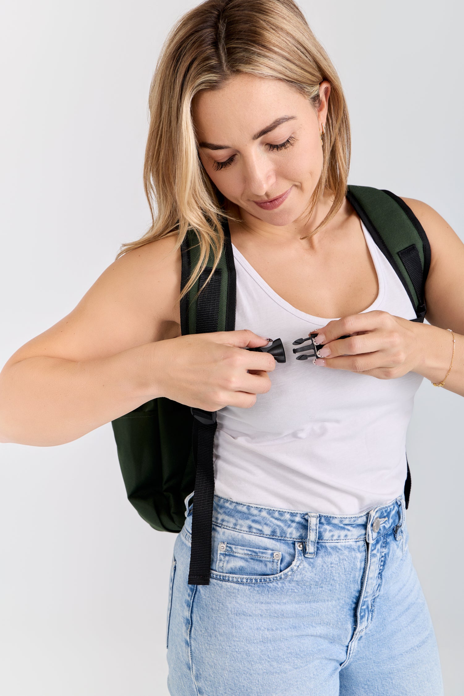 Woman adjusting a black backpack strap against a white background