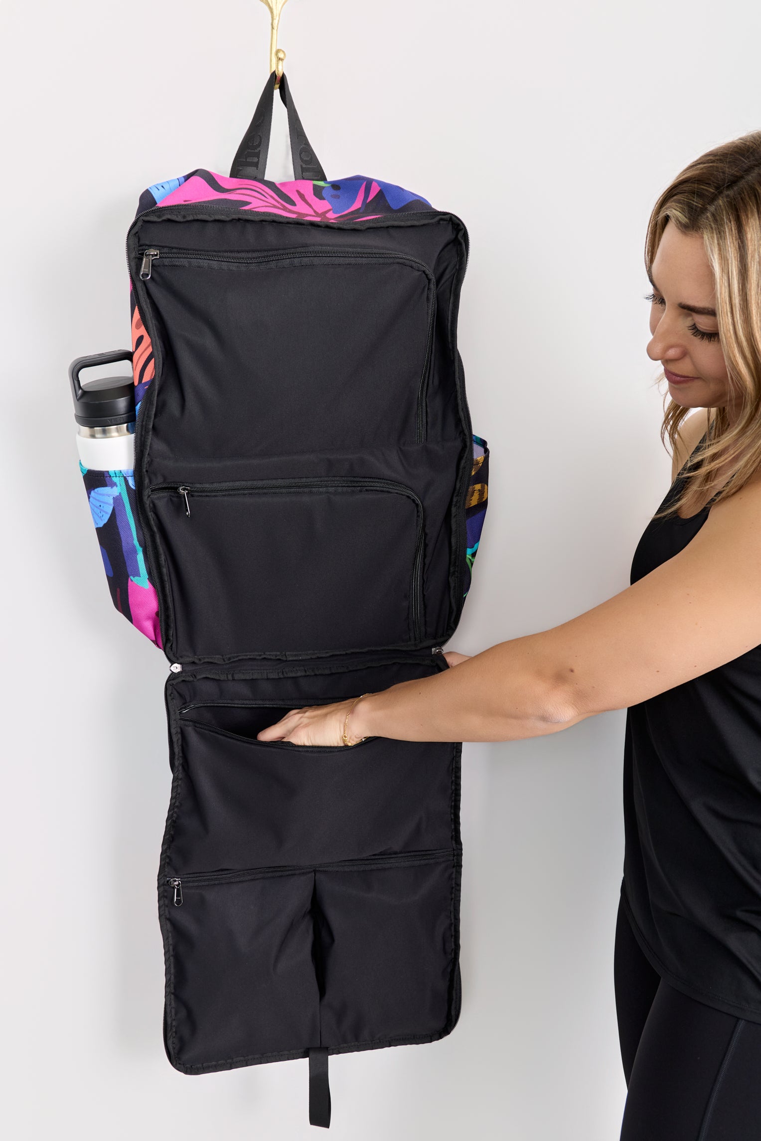 Person interacting with a black backpack on a white background