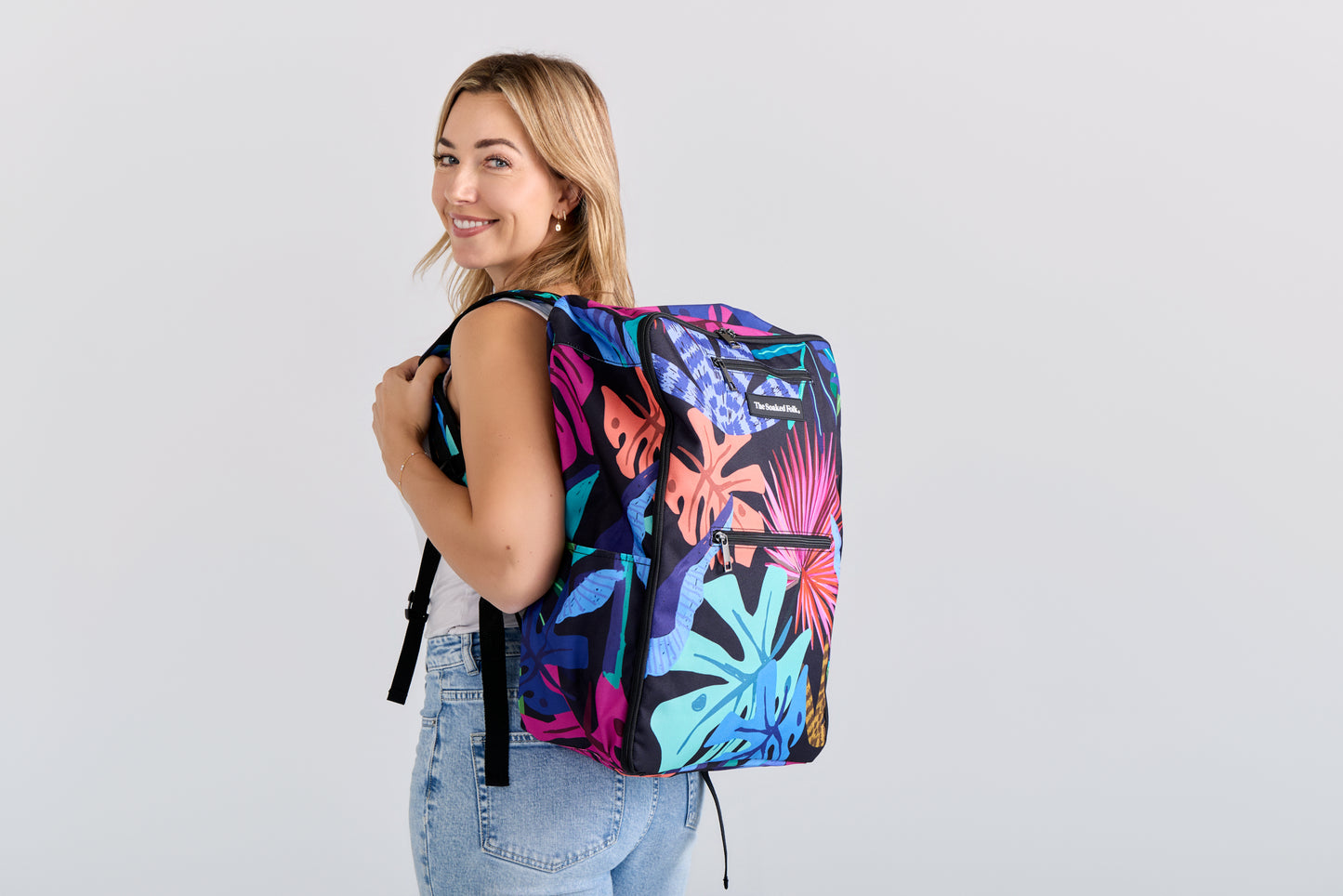 Woman wearing a colorful backpack on a light gray background